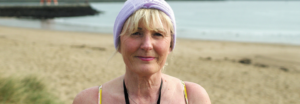 Sue Mountain wearing swimming costume standing on the beach