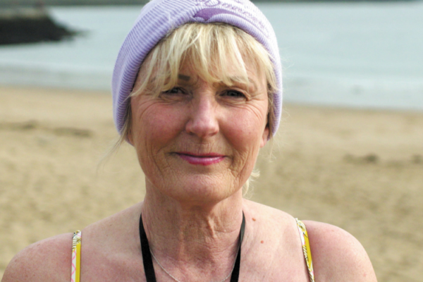 Sue Mountain wearing swimming costume standing on the beach