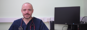 Dr James Crosbie wearing scrubs with stethoscope around his neck